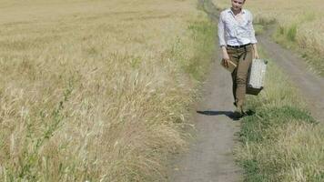 Young lady wearing jeans with luggage walking in the middle of the wheat field video