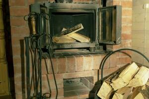 open doors of a cast-iron fireplace insert and firewood stacked inside photo