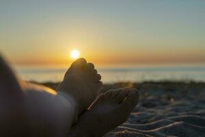 children's feet in the sand on the beach against the background of sea photo