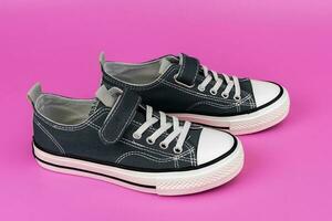 a pair of blue sneakers on a pink background. Fashionable youth shoes photo