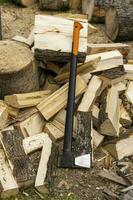 Professional axe and chopped firewood in the yard of the house photo