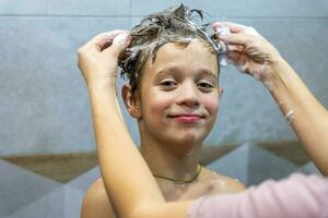 preschooler boy washes his head in the bathroom with shampoo photo