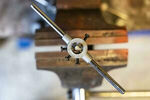 threading on a part clamped in an old iron vise in the workshop photo