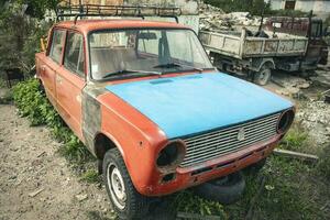 un antiguo roto clásico coche abandonado en el calle. inoxidable antiguo máquina foto