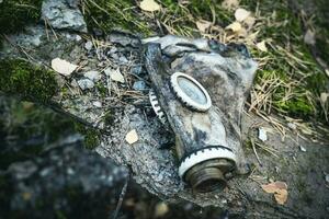 an old used gas mask lying on a large stone photo