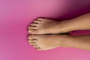 beautiful natural legs of a teenage girl on a pink background photo