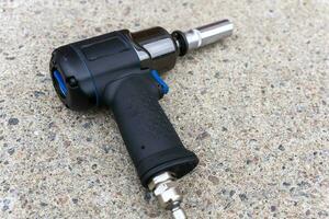 a pneumatic impact wrench with an end head on the concrete floor photo