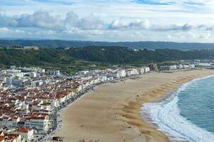 The city of Nazare in Portugal, the symbol of surfing. Coastline and view from above on the town. Tourist place with big waves. photo