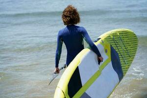 Unrecognizable surfer with paddleboard in sea photo