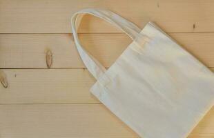 International Plastic Bag Free Day concept. Top view and close up of White cotton bag on wooden background, reuse shopping  bag for stop global warming. photo