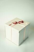 white cardboard gift box tied with a red ribbon on a white background photo