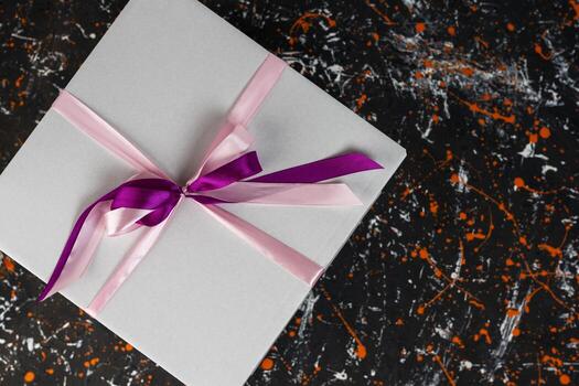 blanco regalo caja atado con un rojo cinta en un manchado de colores antecedentes foto