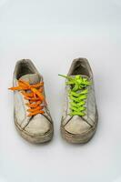 worn old torn white sneakers with colored laces on a white background photo