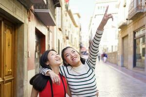 Cheerful ethnic women walking on city street photo