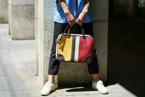 Faceless woman with colorful handbag on street photo