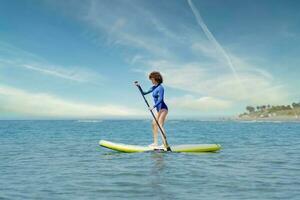 mujer en paddleboard en mar foto