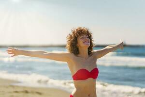 Happy woman in bikini standing on beach photo