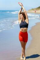 Fit woman stretching body on seashore photo