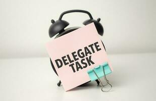 alarm clock with pink sticker with the text delegate task photo