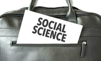 Text SOCIAL SCIENCE writing on white paper sheet in the black business bag. Business concept photo