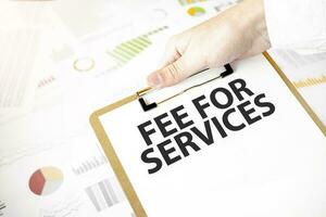 Text fee for services on white paper plate in businessman hands with financial diagram. Business concept photo