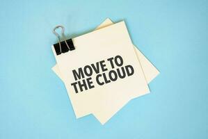 Text MOVE TO THE CLOUD on sticky notes with copy space and paper clip isolated on red background.Finance and economics concept. photo