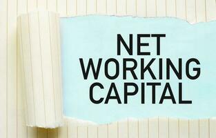 Text NET WORKING CAPITAL appearing behind torn white paper photo