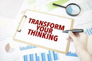 Text TRANSFORM YOUR THINKING on white paper sheet and marker on businessman hand on the diagram. Business concept photo