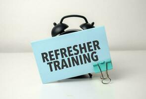 refresher training is written in a blue sticker near a black alarm clock photo