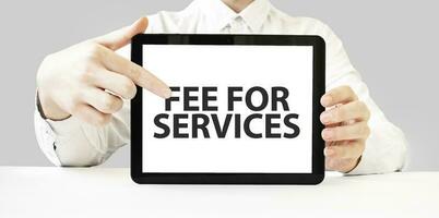 Text fee for services on tablet display in businessman hands on the white background. Business concept photo