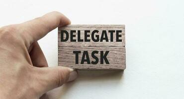 Hand of a businessman holding wooden blocks. Conceptual image. Text delegate task concept business succeed. photo