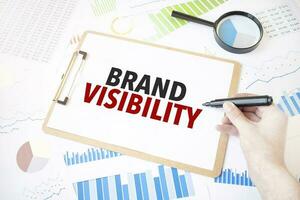 Text brand visibility on white paper sheet and marker on businessman hand on the diagram. Business concept photo