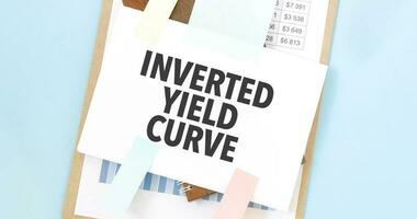 Paper plate with text take INVERTED YIELD CURVE. Diagram, notepad and blue background photo