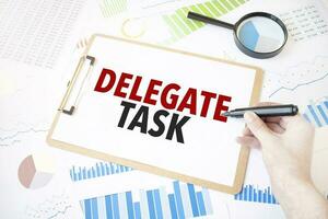 Text delegate task on white paper sheet and marker on businessman hand on the diagram. Business concept photo