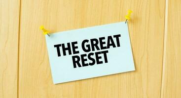 THE GREAT RESET sign written on sticky note pinned on wooden wall photo