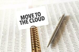 Text MOVE TO THE CLOUD on paper card,pen, financial documentation on table - business, banking, finance and investment concept. close up of stock market chart. photo