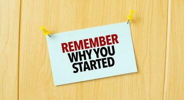 remember why you started sign written on sticky note pinned on wooden wall photo