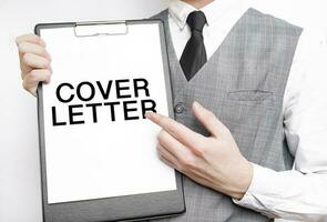 COVER LETTER inscription on a notebook in the hands of a businessman on a grey background, a man points with a finger to the text photo