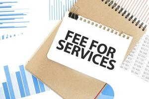 Text fee for services on white paper sheet and brown paper notepad on the table with diagram. Business concept photo