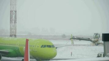 NOVOSIBIRSK, RUSSIAN FEDERATION NOVEMBER 14, 2020 - Shot of spraying de icing fluids onto the plane of S7 Airlines in Tolmachhevo Airport on snowy winter day video