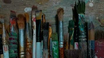 Male artist hand with paintbrush set above dirty worktop video