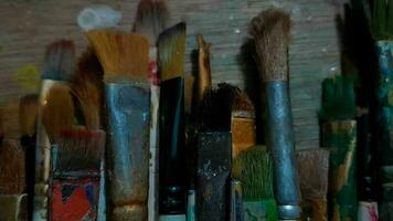 Male artist hand with paintbrush set above dirty worktop video