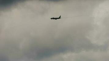 Civil aircraft approaching landing, long shot. Airliner silhouette in dark cloudy sky at dusk video