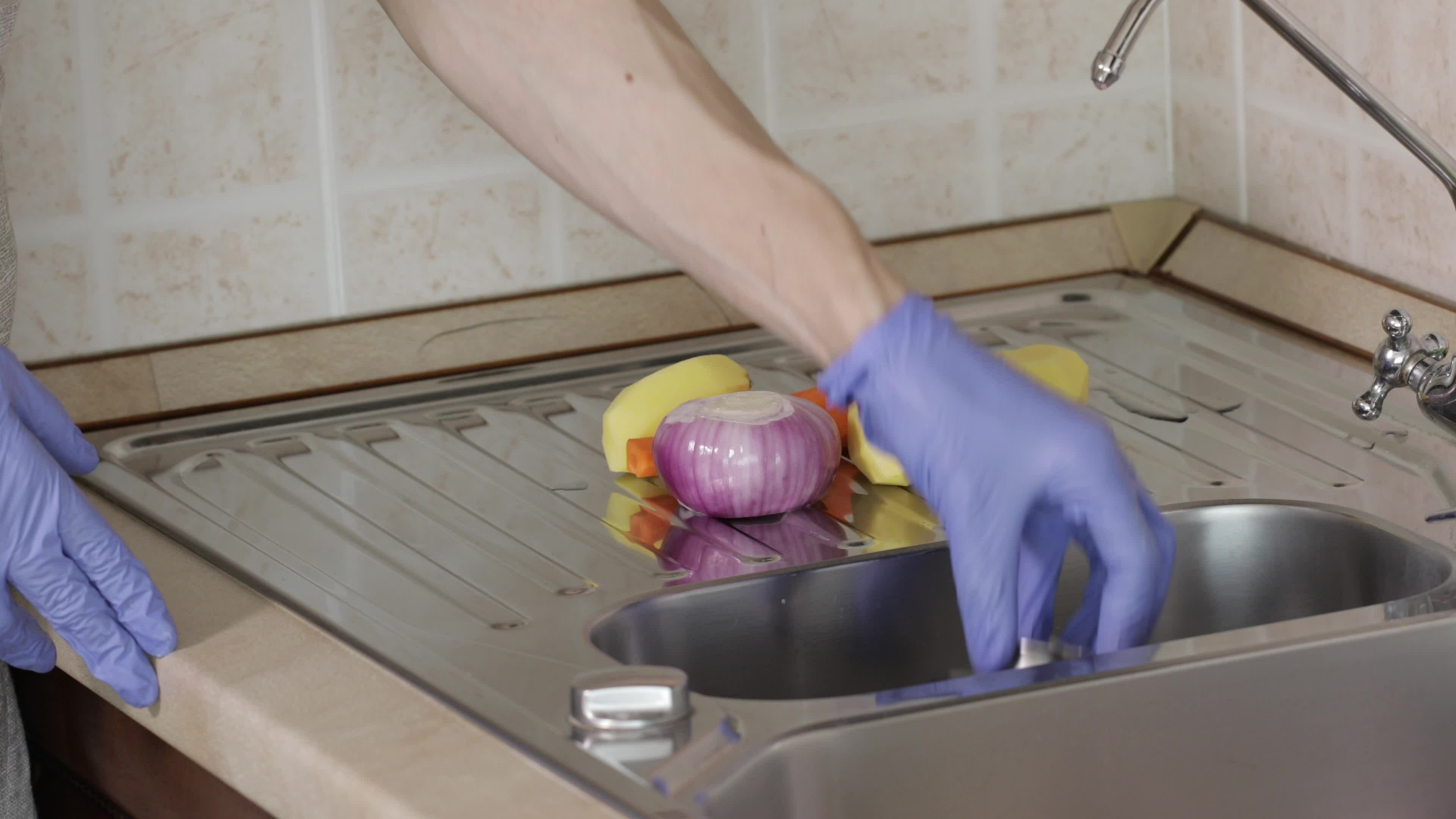 Woman puts vegetables in the sink compartment and fills it up with
