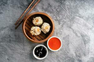 Chinese steamed dumplings or  Dim Sum in bamboo steamer on dark abstract background photo