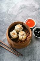 Chinese steamed dumplings or  Dim Sum in bamboo steamer on dark abstract background photo