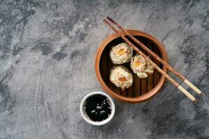 Chinese steamed dumplings or  Dim Sum in bamboo steamer on dark abstract background photo