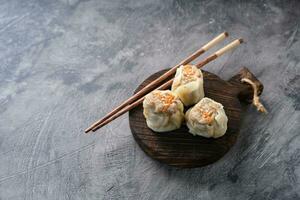 Chinese steamed dumplings or  Dim Sum in bamboo steamer on dark abstract background photo