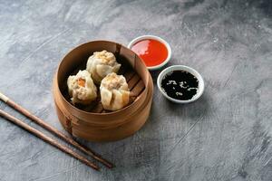 Chinese steamed dumplings or  Dim Sum in bamboo steamer on dark abstract background photo