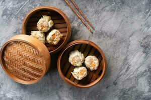 Chinese steamed dumplings or  Dim Sum in bamboo steamer on dark abstract background photo